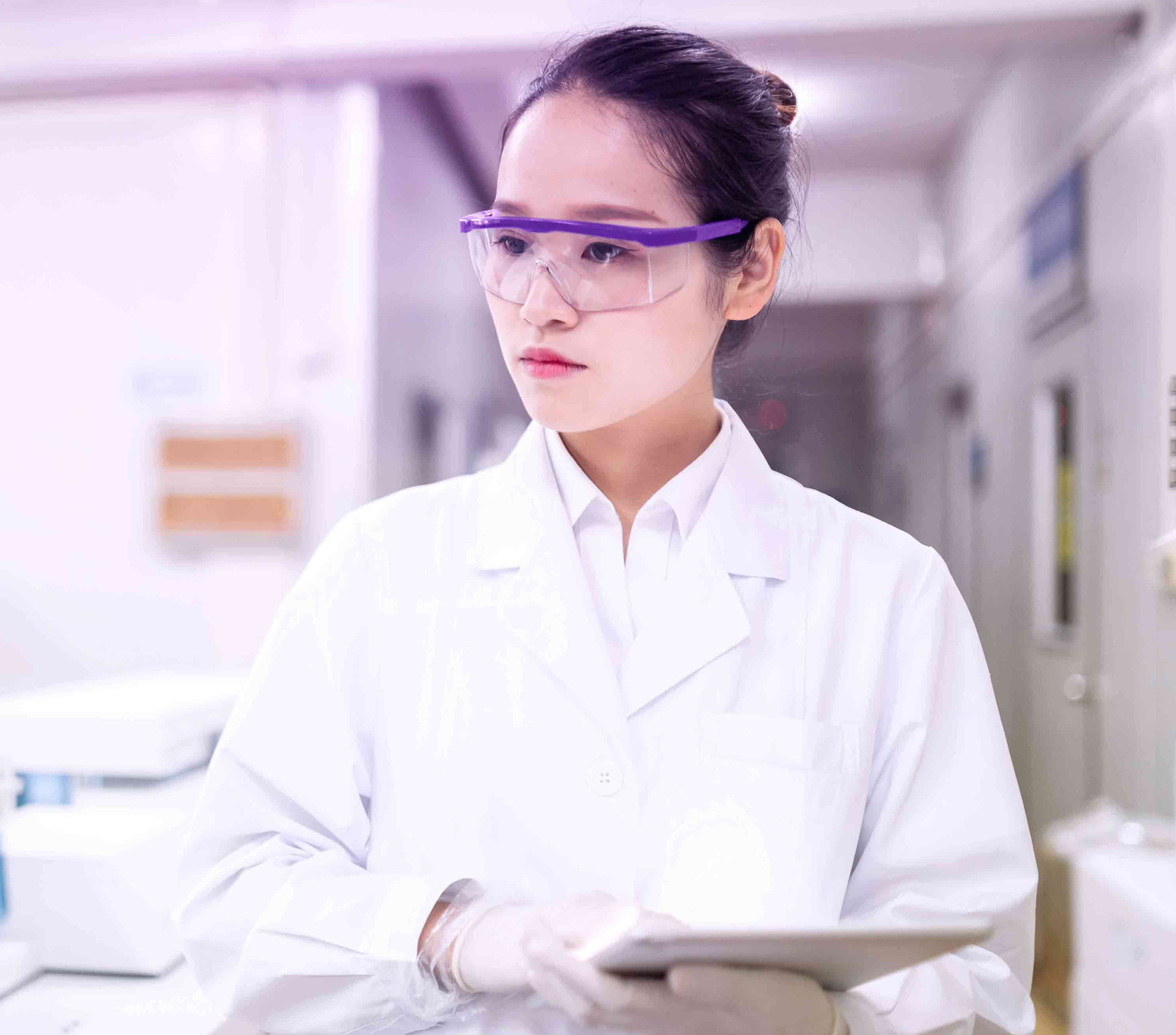 Woman in a lab wearing protective equipment and holding papers