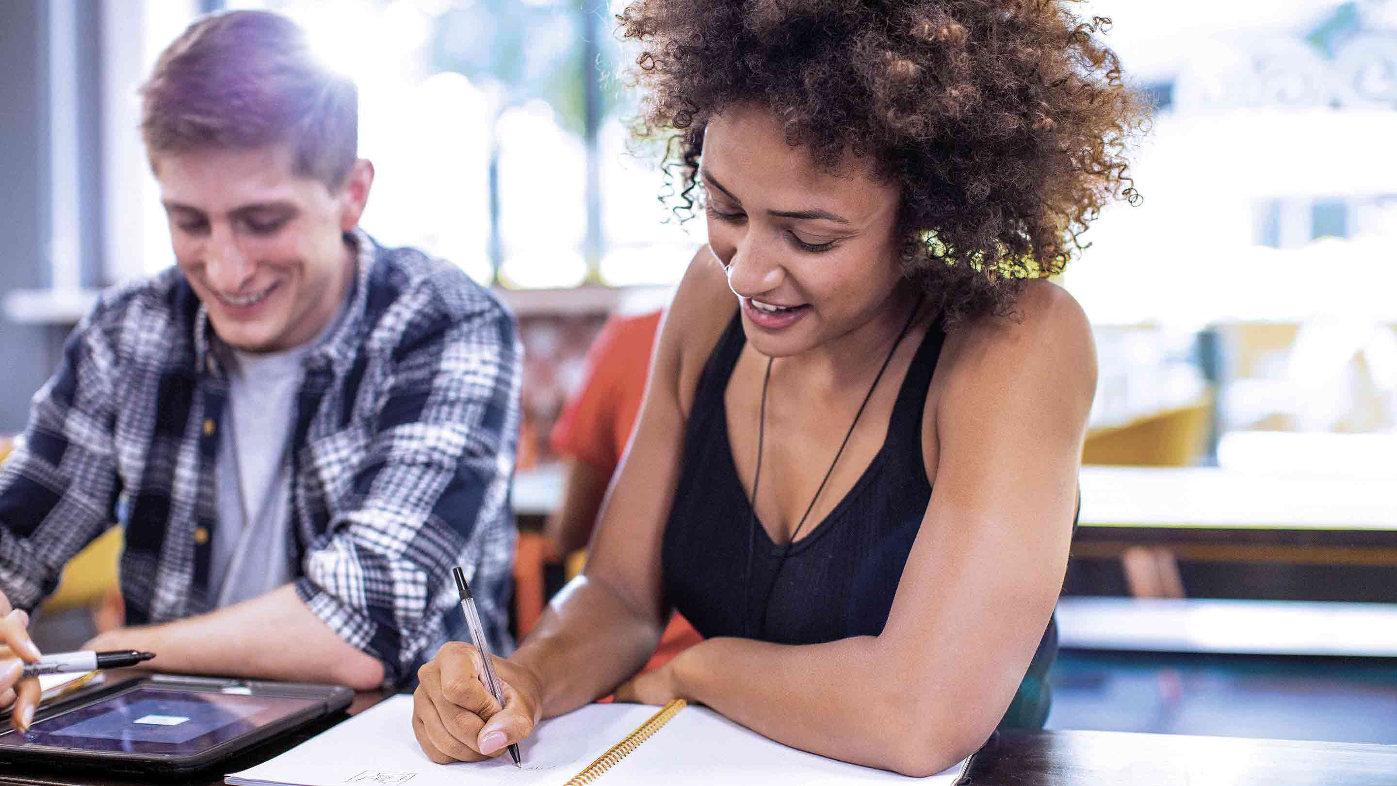 Two casually dressed students work over a notebook