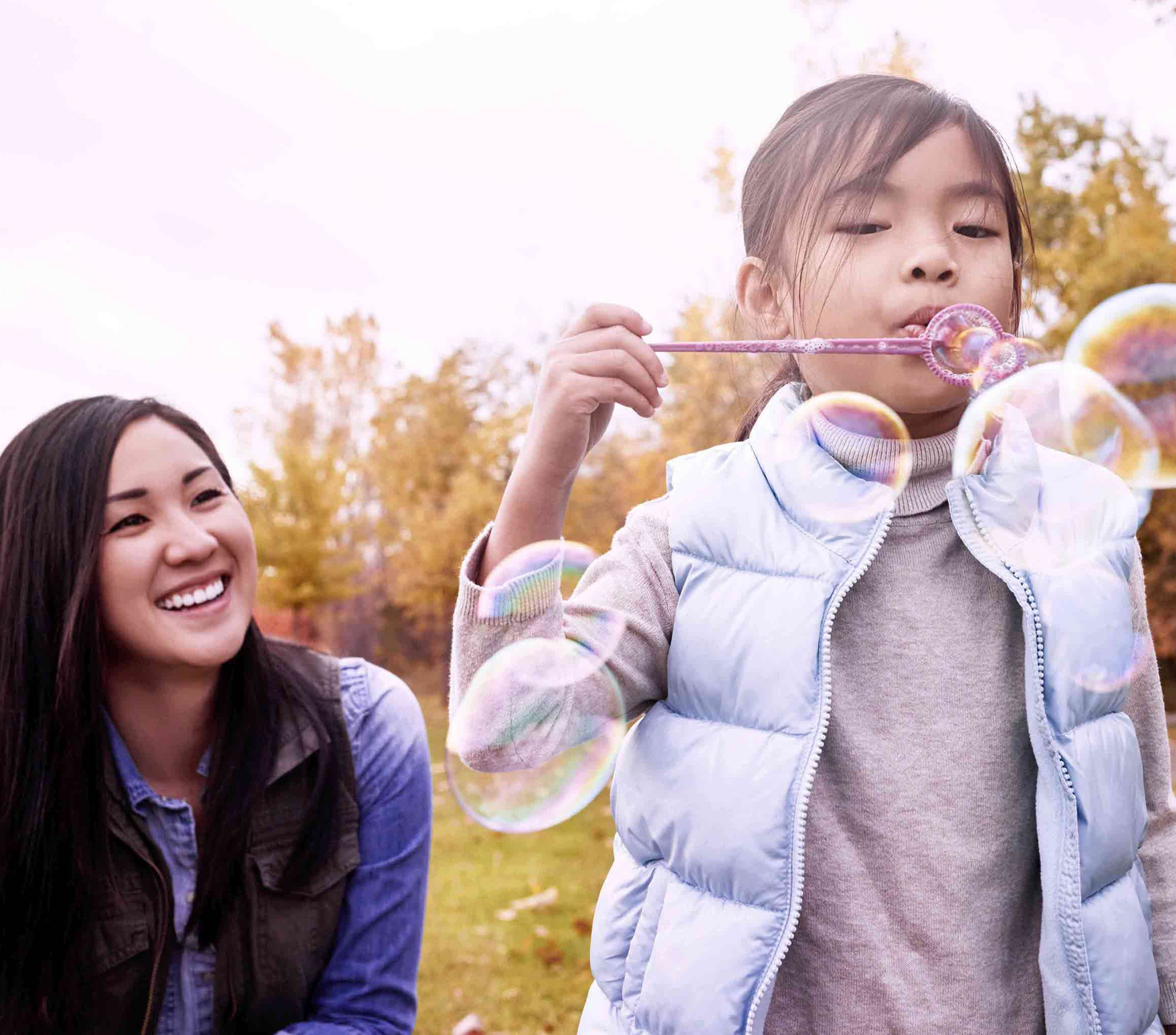 Woman with child blowing bubbles in the park 