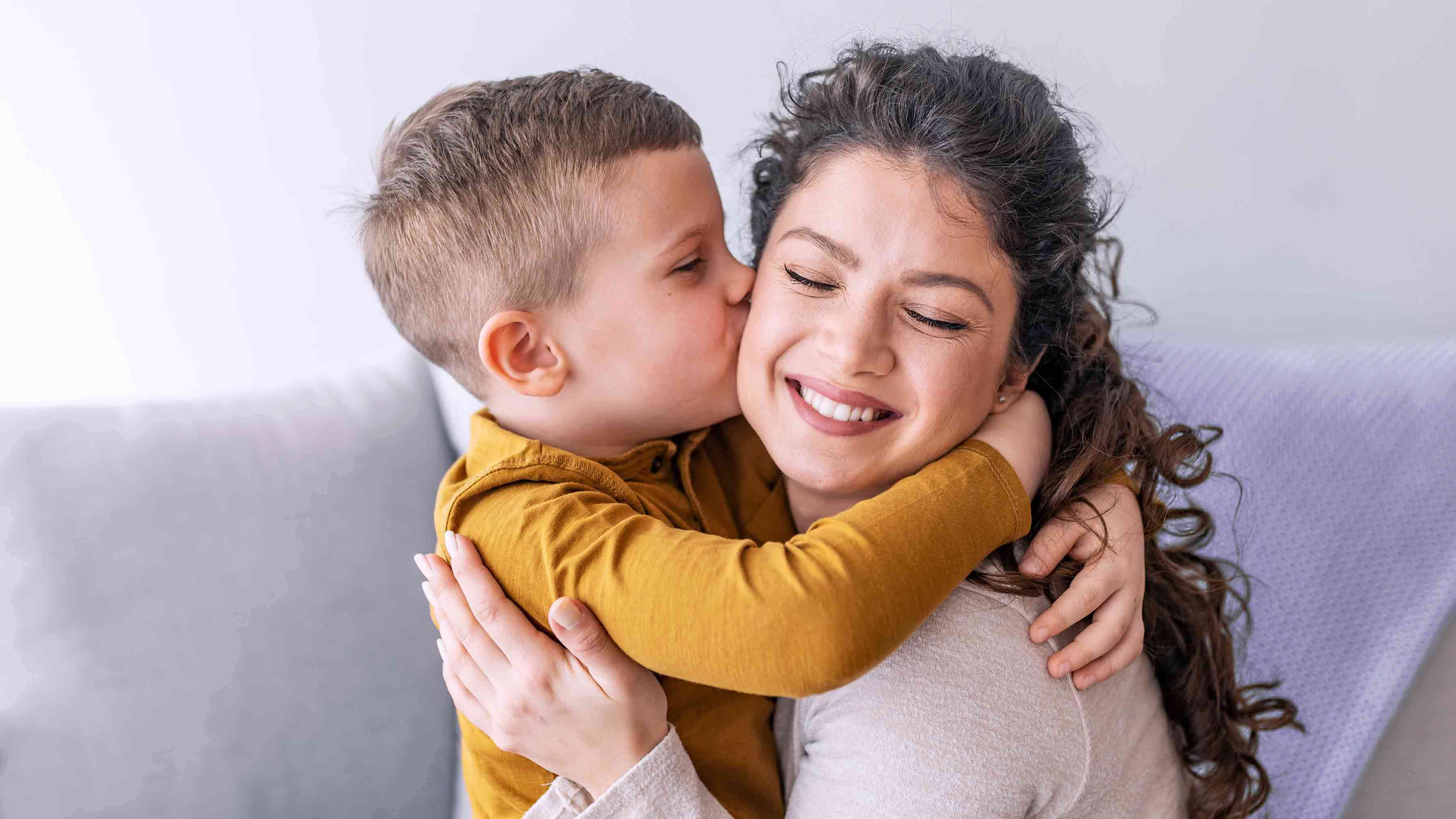 Young child hugging and kissing his smiling mother