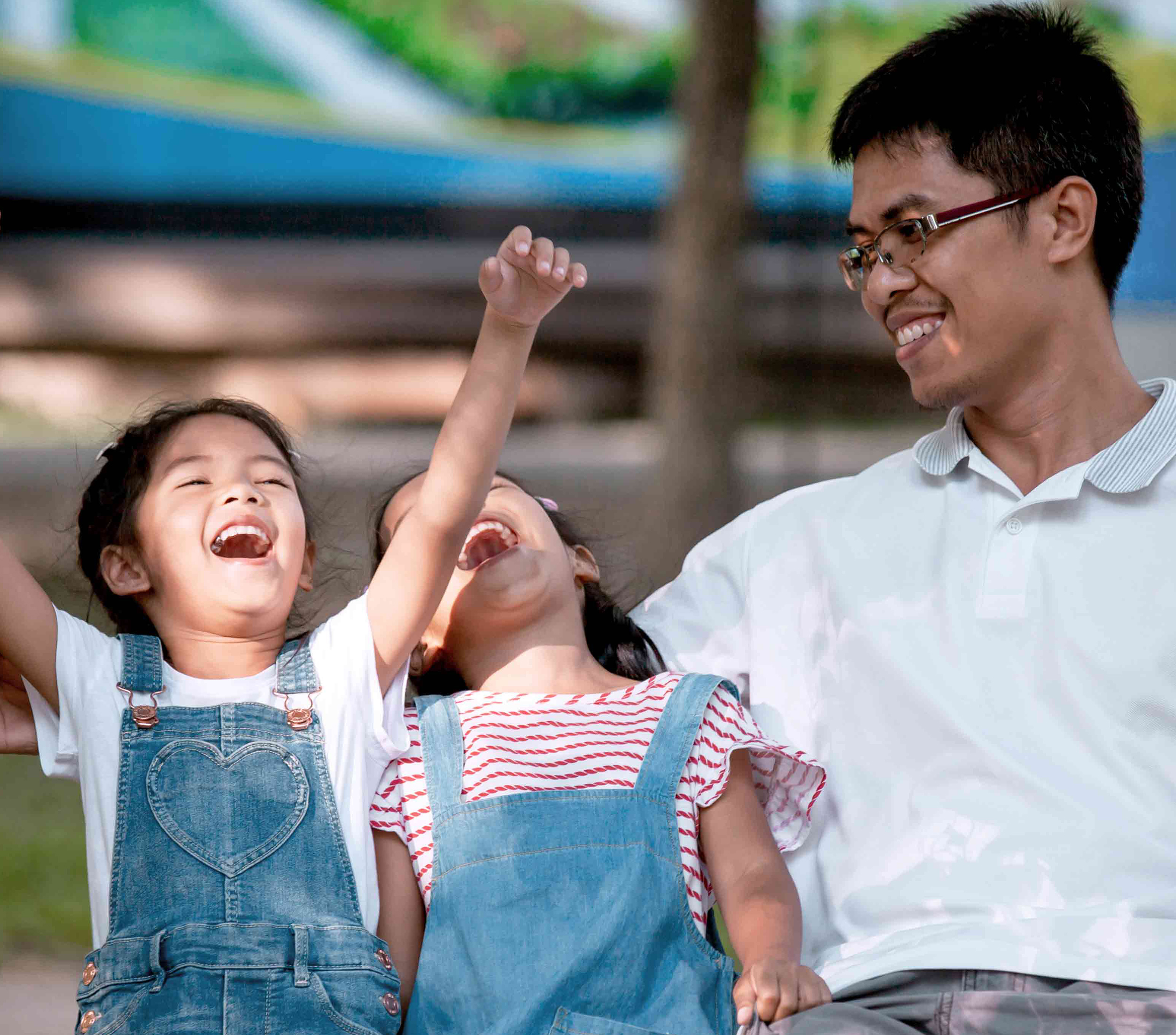 Man and his two daughters laughing and cheering on a bench